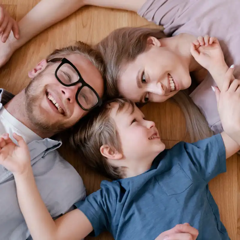 Eine Familie liegt lachend auf dem Fußboden Eine Familie liegt lachend auf dem Fußboden